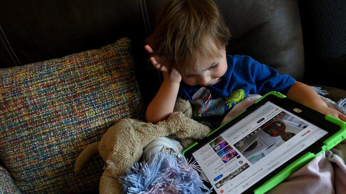A young child formerly in foster care snuggles with his lovey and a tablet while getting over a cold. His parents have fostered him since birth and ended up adopting him.
