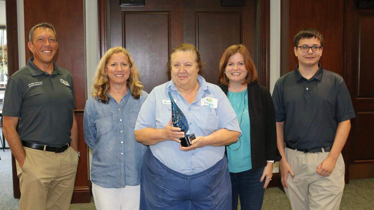 Judges, from left, George Kruse, Mandi Rice, Tara Poulton and Ethan Greenbaum stand with Punta Gorda representative Susanna Haslinger (center) whose drinking water was judged best during competition March 25, 2022, among six regional water utilities.