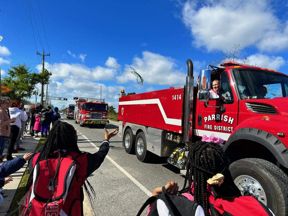On Saturday, Jan. 14, 2023, the Dr. Martin Luther King Jr. Parade returned to Palmetto. A student reaches for beads as a Parrish Fire Department engine passes by.
