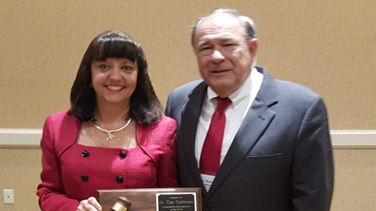 Tina Calderone receives a commemorative plaque from CFPSBC Chairman Dave Miner. PHOTO PROVIDED