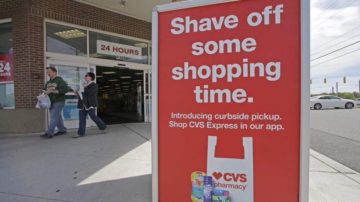 In this April 15, 2016, photo, customers leave past a sign promoting CVS Express at a CVS store in Harrisburg, N.C. Customers can shop via an app on their smartphone and will receive a text when their order is ready to be picked up. (AP Photo/Chuck Burton)