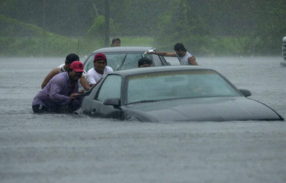 In this 2001 file photo, residents push cars through flooded streets as they are evacuated from the Oakridge Apartments in Palmetto. The area was flooded as Tropical Storm Gabrielle moved across Manatee County.