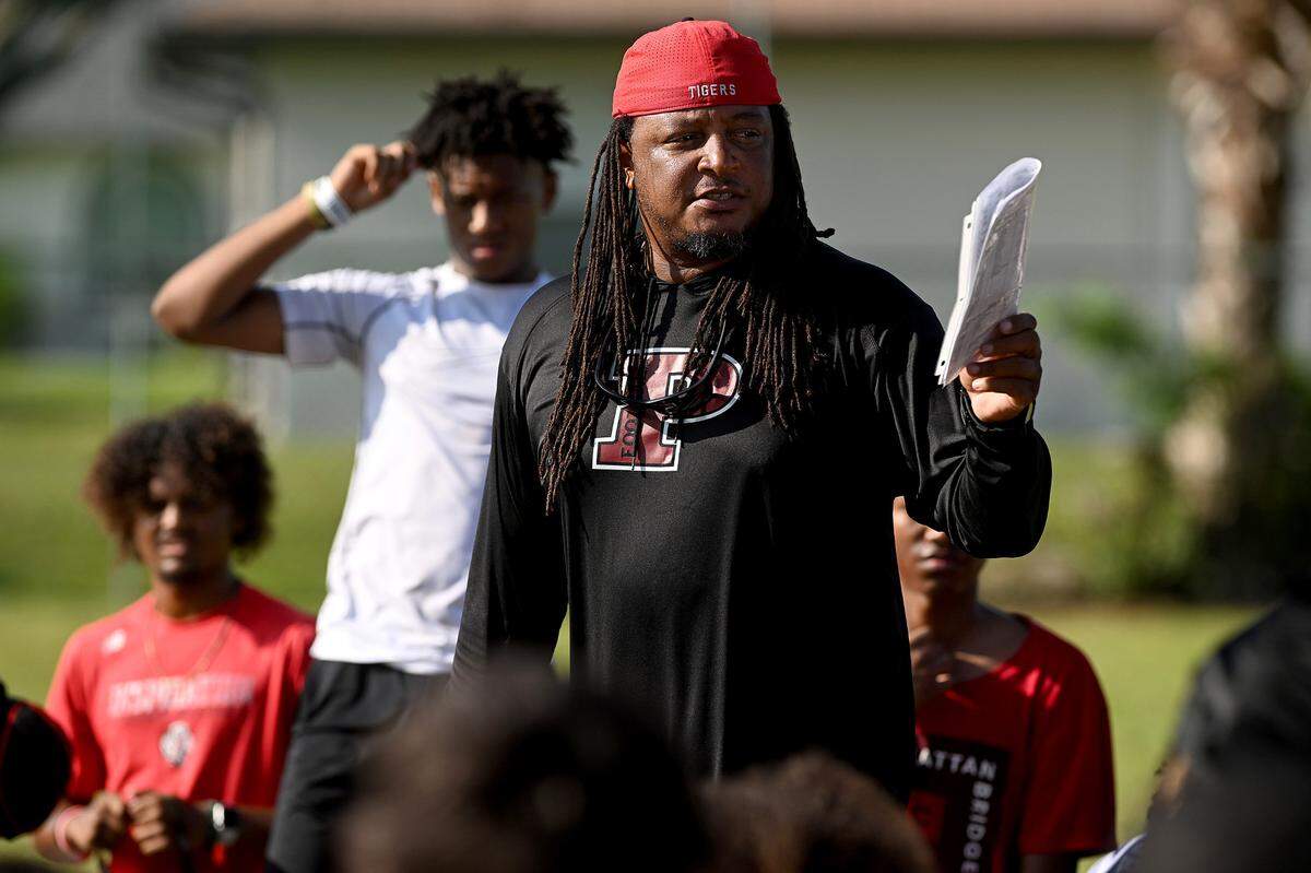 The Palmetto High football team practices at the Palmetto Charter School in the morning to try to beat the heat of the afternoons. Coach Rashad West talks with players after practice.