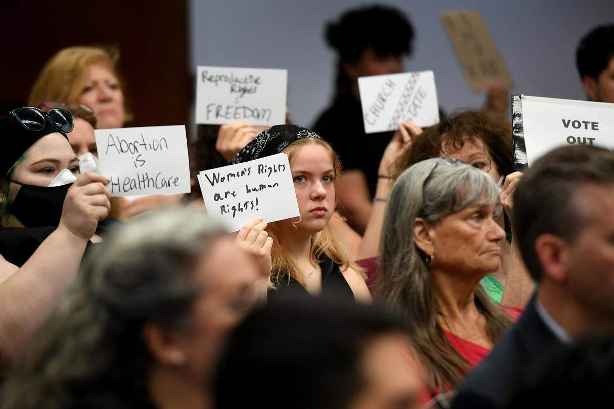 Abortion rights protesters hold up signs during a public meeting of the county commission on Tuesday, July 26, 2022.
