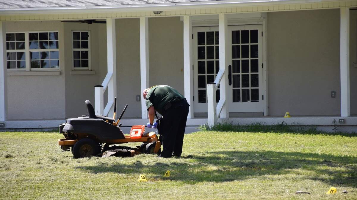 07/09/21--A deputy within the Manatee County Sheriff’s Office’s Crime Scene Unit inspects the lawnmower in a Terra Ceia neighborhood on Friday afternoon. The sheriff’s office said a 63-year-old man was stabbed multiple times by a “suspicious” shirtless man, who died after the victim fought back with his son. The attacker sustained a “substantial head injury” and died at the scene, investigators say.