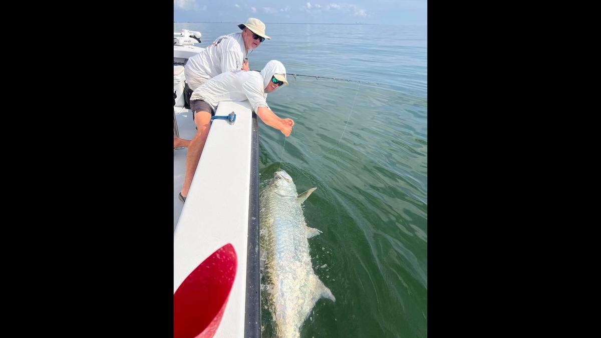 AMI Exercursions charter captain Nathan Costello and angler Mike are pictured with a tarpon caught fishing in Tampa Bay on a threadfin.