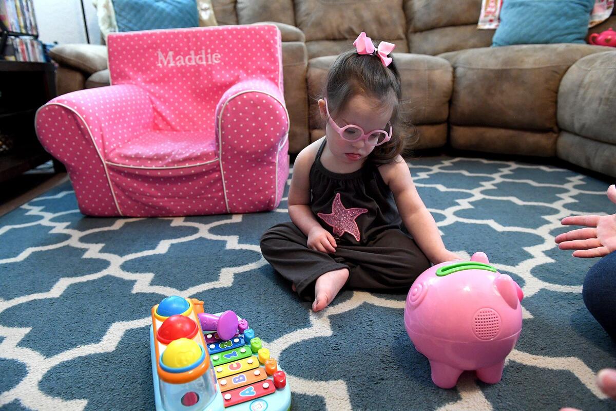Maddie Gordon, 2, plays with her favorite toys in her living room, pink bow holding a curled ponytail that bounces as she moves. Maddie’s pediatric therapy program at Blake Medical will soon be moving to Manatee Memorial Hospital.
