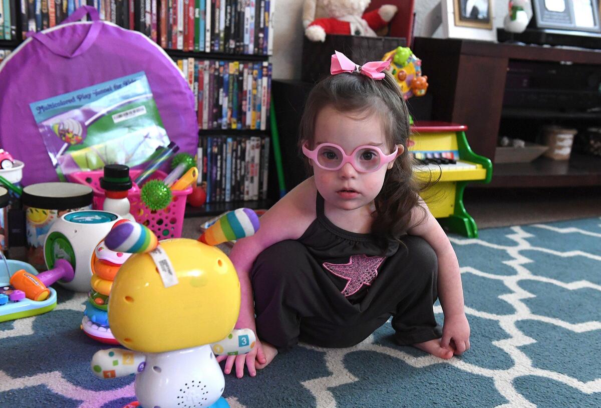 Maddie Gordon, 2, plays with her favorite toys in her living room, pink bow holding a curled ponytail that bounces as she moves. Maddie’s pediatric therapy program at Blake Medical will soon be moving to Manatee Memorial Hospital.
