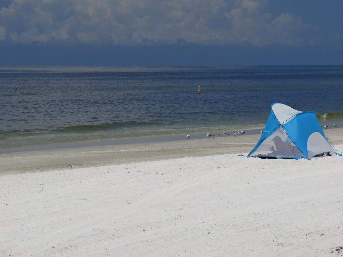 A lone beachgoer seeks shade under a tent on Cortez Beach in this Bradenton Herald file photo. According to the FWC, concentrations of red tide are more than 25 percent higher in Manatee County than they were last week.