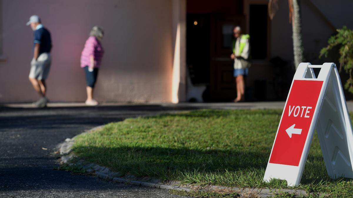 Voters are greeted with an election worker strumming a guitar in front of Precinct 323 at the Elks Lodge on the morning of the Florida primaries in Bradenton.