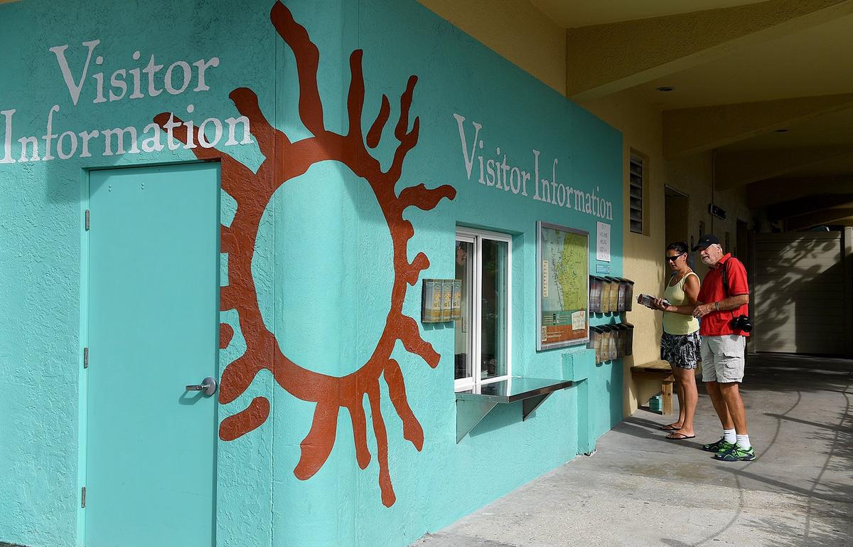 Red tide has hit area businesses hard, keeping crowds away from the island. But owners have hopes that Labor Day weekend business will be strong. Visitors grab some literature from the information center at the Manatee Public Beach Thursday morning.