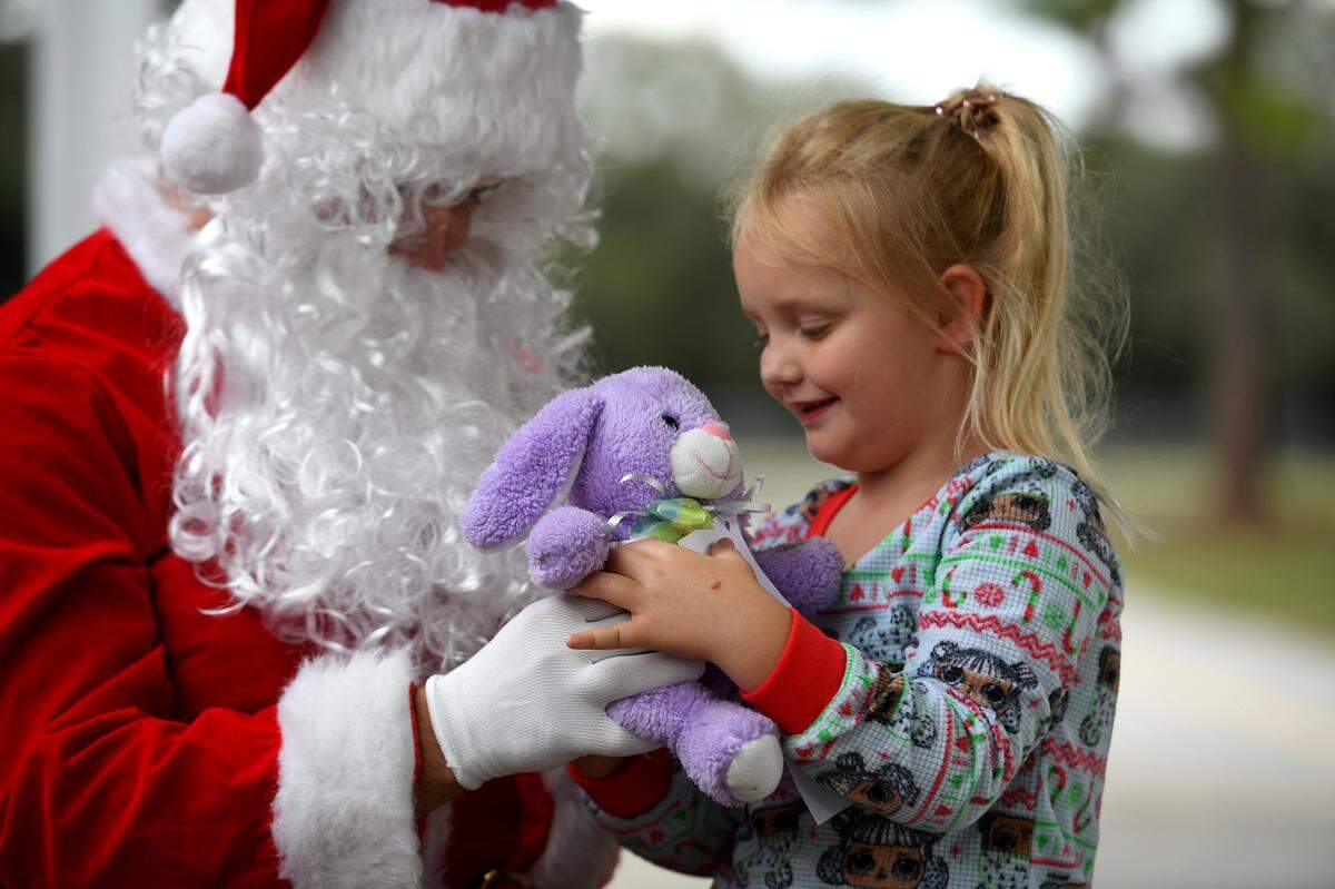 12/20/21—Skylar Whightsel accepts a purple bunny from Santa, who arrived on an East Manatee Fire Rescue truck to delight of pre-kindergarteners and ESE students at Bashaw Elementary School.