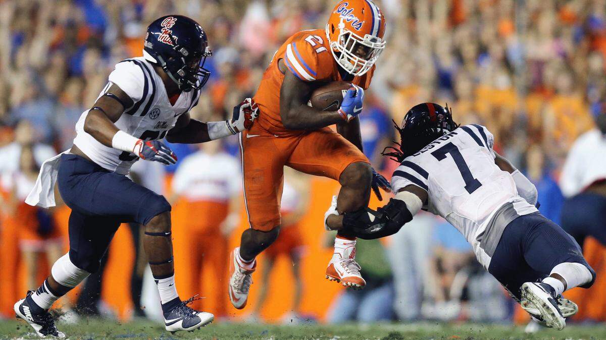 Florida running back Kelvin Taylor (21) rushes for yardage between Mississippi linebacker DeMarquis Gates (31), left, and defensive back Trae Elston (7) during the first half of an NCAA college football game Saturday, Oct. 3, 2015, in Gainesville, Fla. (AP Photo/Gary McCullough)