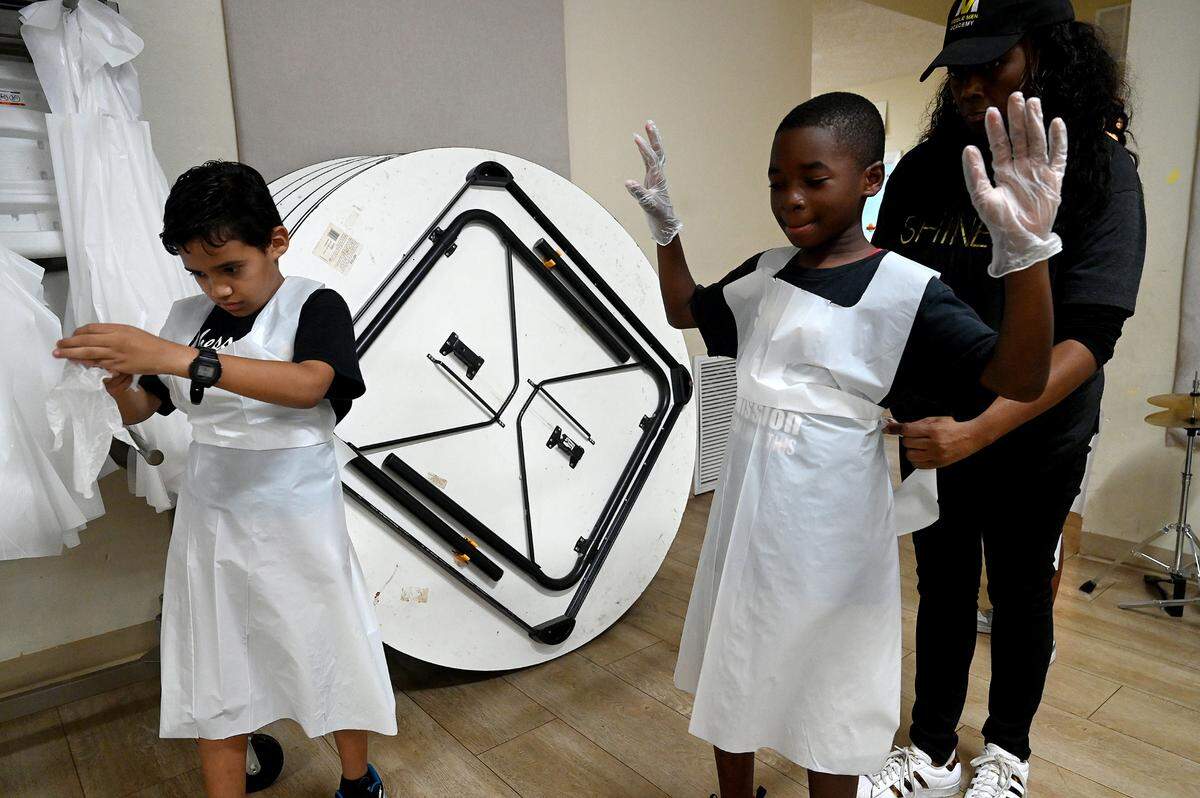 Students put on gloves and aprons to make apple pies for their families’ Thanksgiving celebrations at Visible Men Academy on Friday, Nov. 17, 2023.