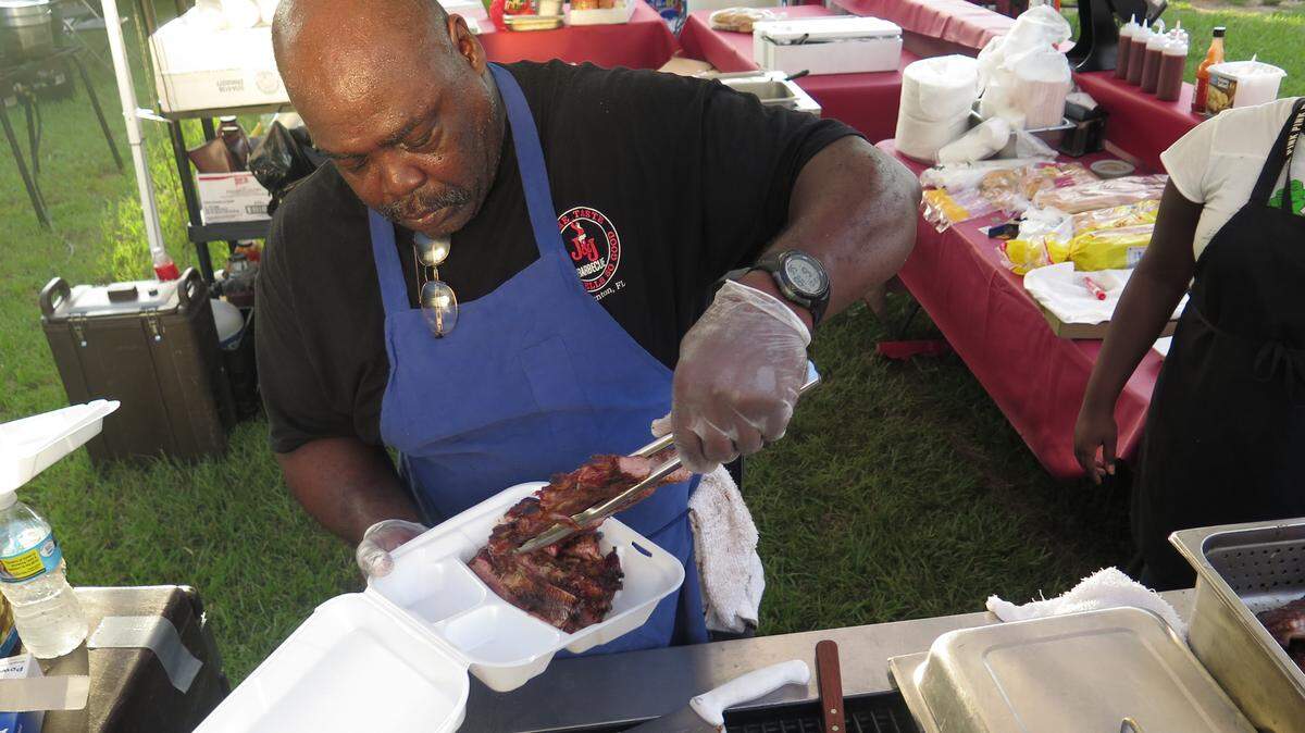 Avery Burke, 56, of Bradenton, prepares a ribs meal Friday evening at the J & J Bar-B-Que stand during the Gulf Coast Rhythm & Ribs Music Fest. The festival, held in the parking lot of the McKechnie Field, runs through this Sunday. 
 AMARIS CASTILLO/Bradenton Herald