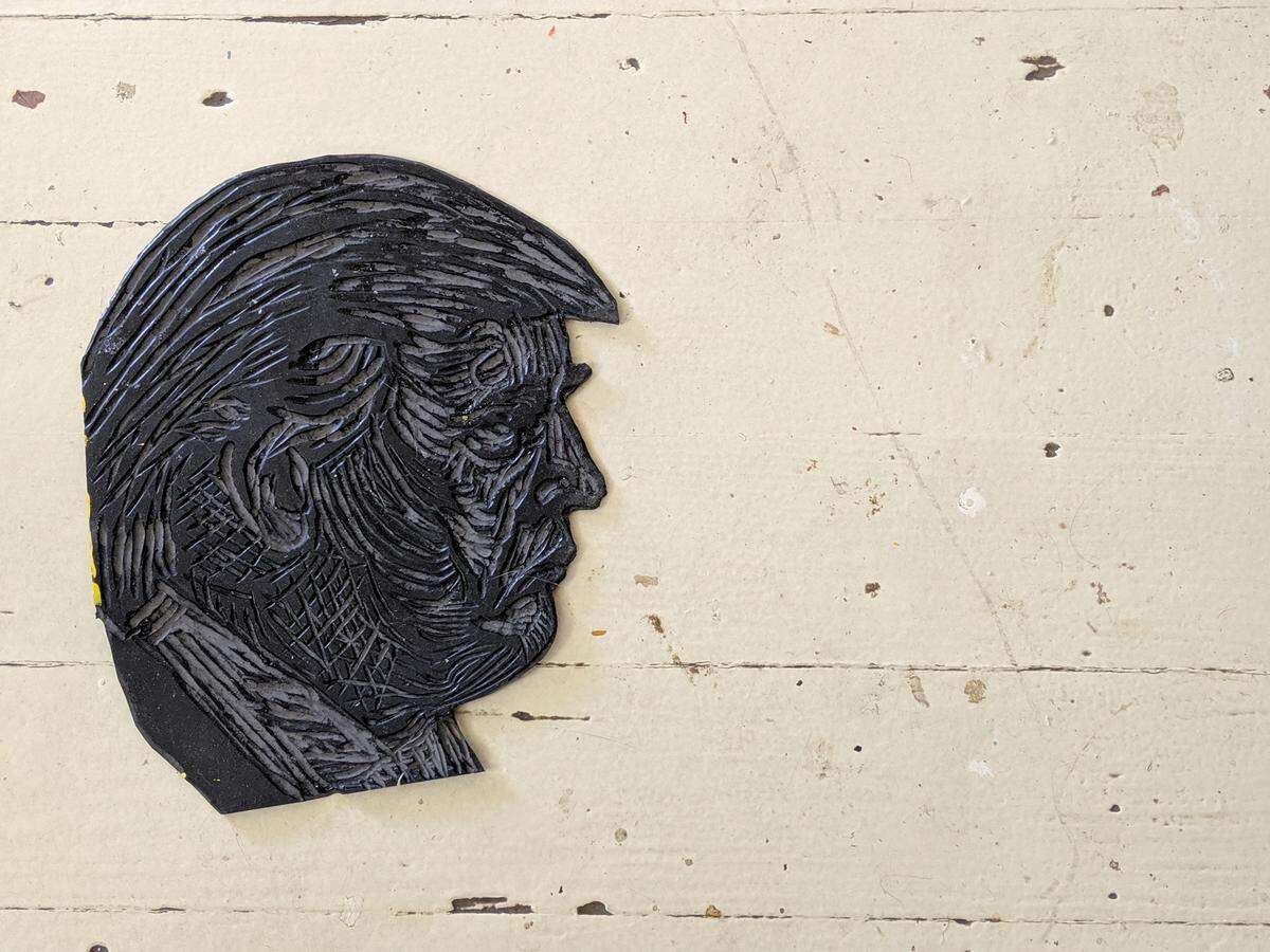 A linocut of Donald Trump, handmade by local artist Susan Curry, was used to create protest shirts with slogans like “Impeach Trump.”