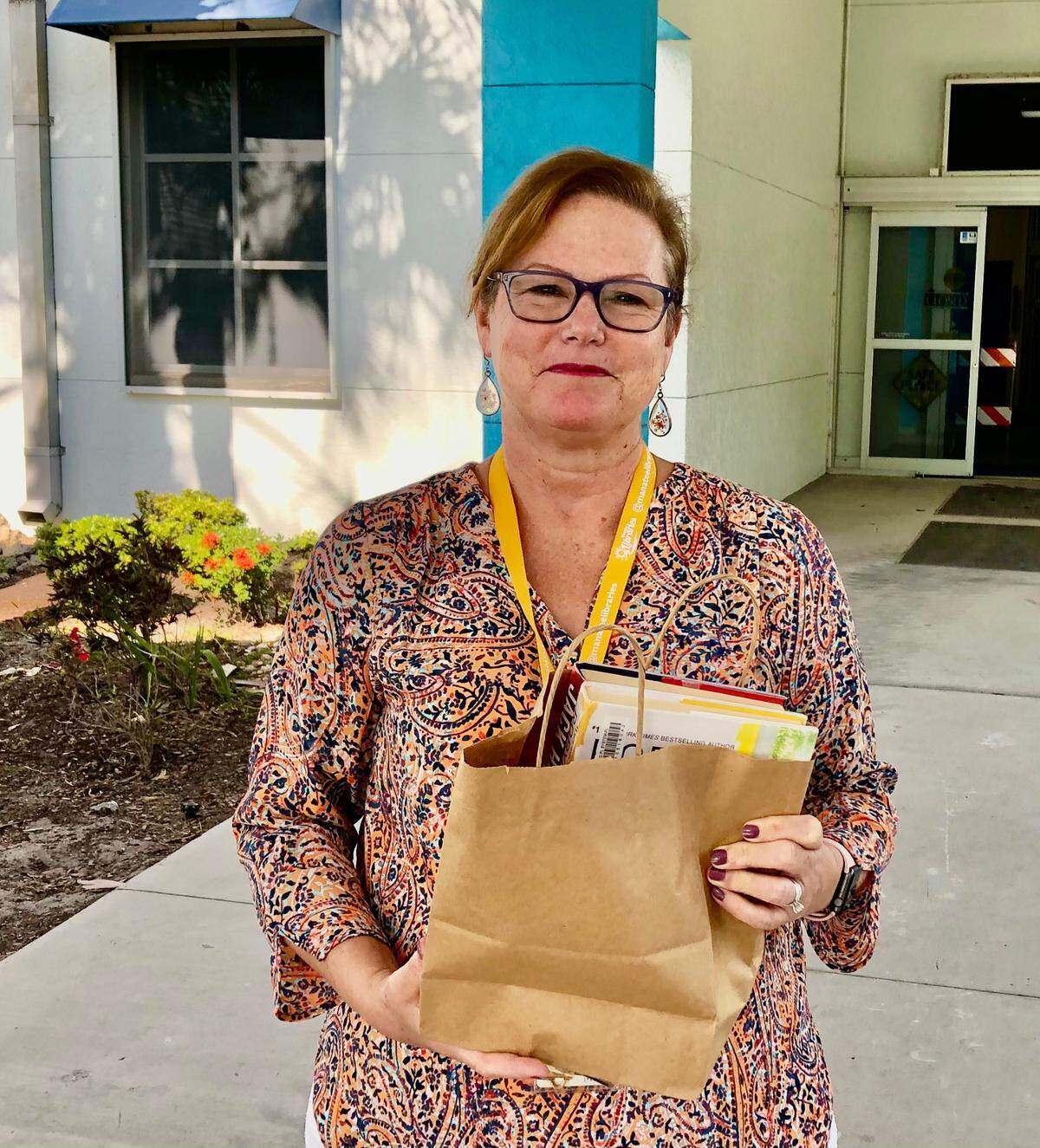 5/21/2021--While Braden River Branch Library will be closed to walk-in visitors during expansion and renovation construction, patrons can take advantage of curbside service. Mary Frueh, assistant library supervisor, shows how library staff will deliver items to drivers on the east side of the library.