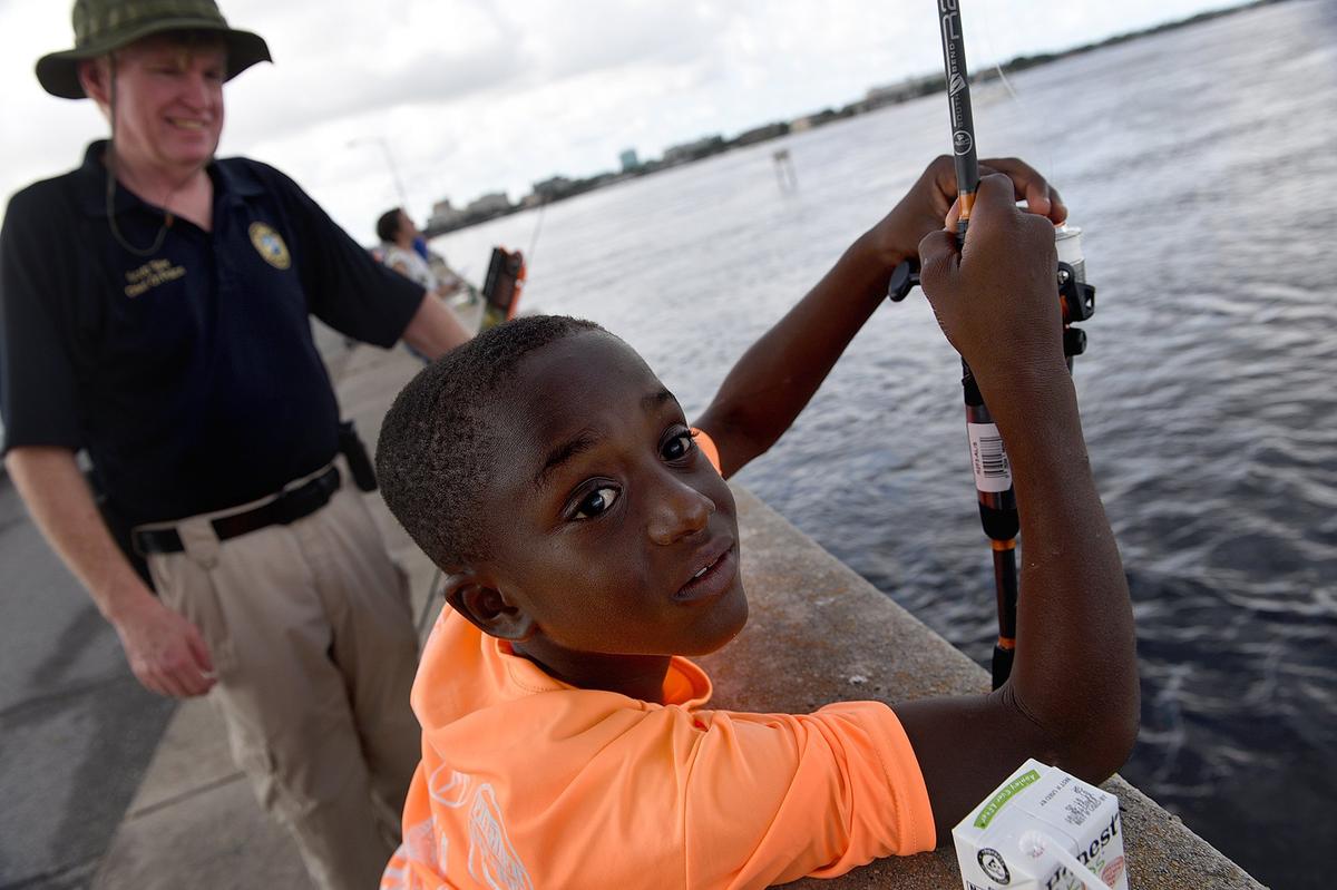 Maurice Carter, 9, fishes with Palmetto Police Chief Scott Tyler during the Manatee Bridging the Gap 2018 Youth Fishing Tournament on the Green Bridge in Palmetto Thursday morning.
