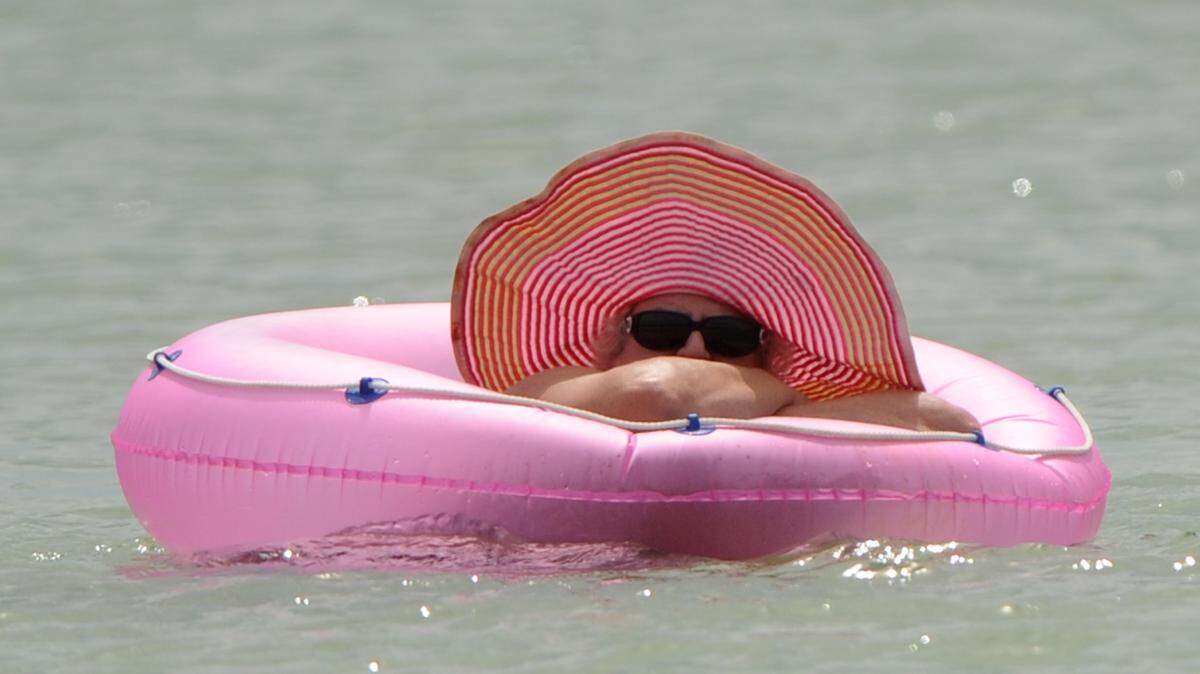 A woman floats in a pink hat and tube as she enjoys a day in the sun and pleasant temperatures Friday on Holmes Beach. 
 GRANT JEFFERIES/Bradenton Herald