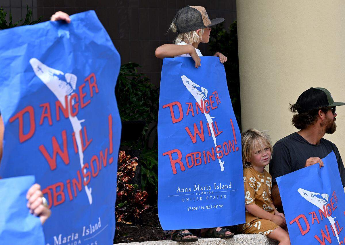 The Bystrom family holds signs together Friday in downtown Bradenton. Gov. Ron DeSantis signed a law Friday that allows Manatee County to build Anna Maria Island beach parking garage despite protests from residents.
