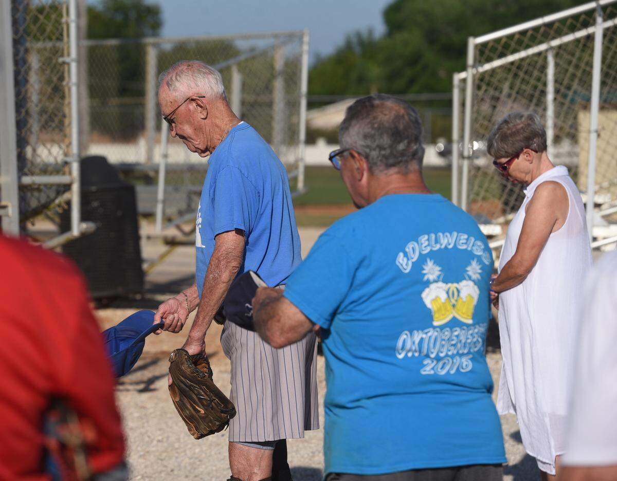 Members of the Bradenton Senior Softball League bow their heads in a moment of silence for a player who recently died.