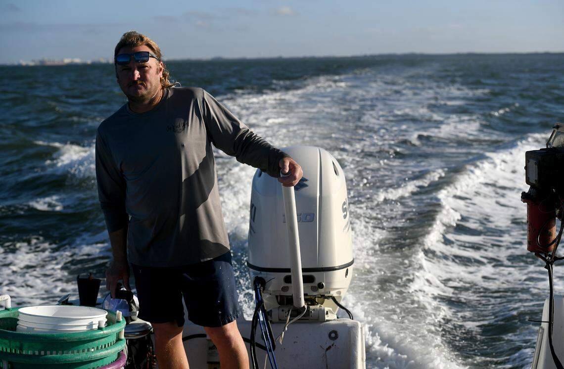 12/15/21—D.J. Strott guides his Carolina skiff through the waters of Tampa Bay to get to where his clams are growing in the shallow waters. The seedling clams are put into the shallow waters, and pulled up months later when they’re ready.