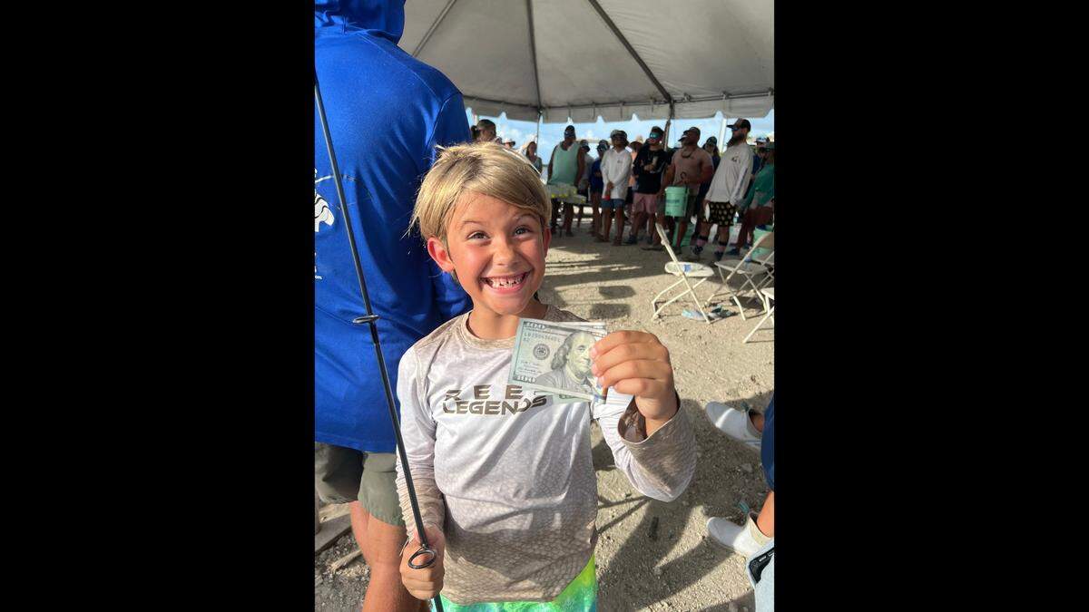 7-year-old angler Waylon Gretenhardt poses with the $200 cash prize he won for being the youngest contestant in the Big Art Memorial Snook Tournament in July.