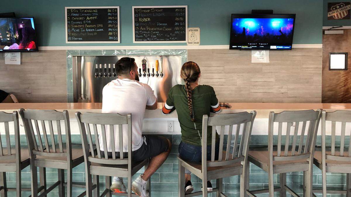 A couple enjoy a beer and watch sports along the 35-foot bar at 3 Car Garage Brewing, which opened recently at 8405 Heritage Green Way, Bradenton.