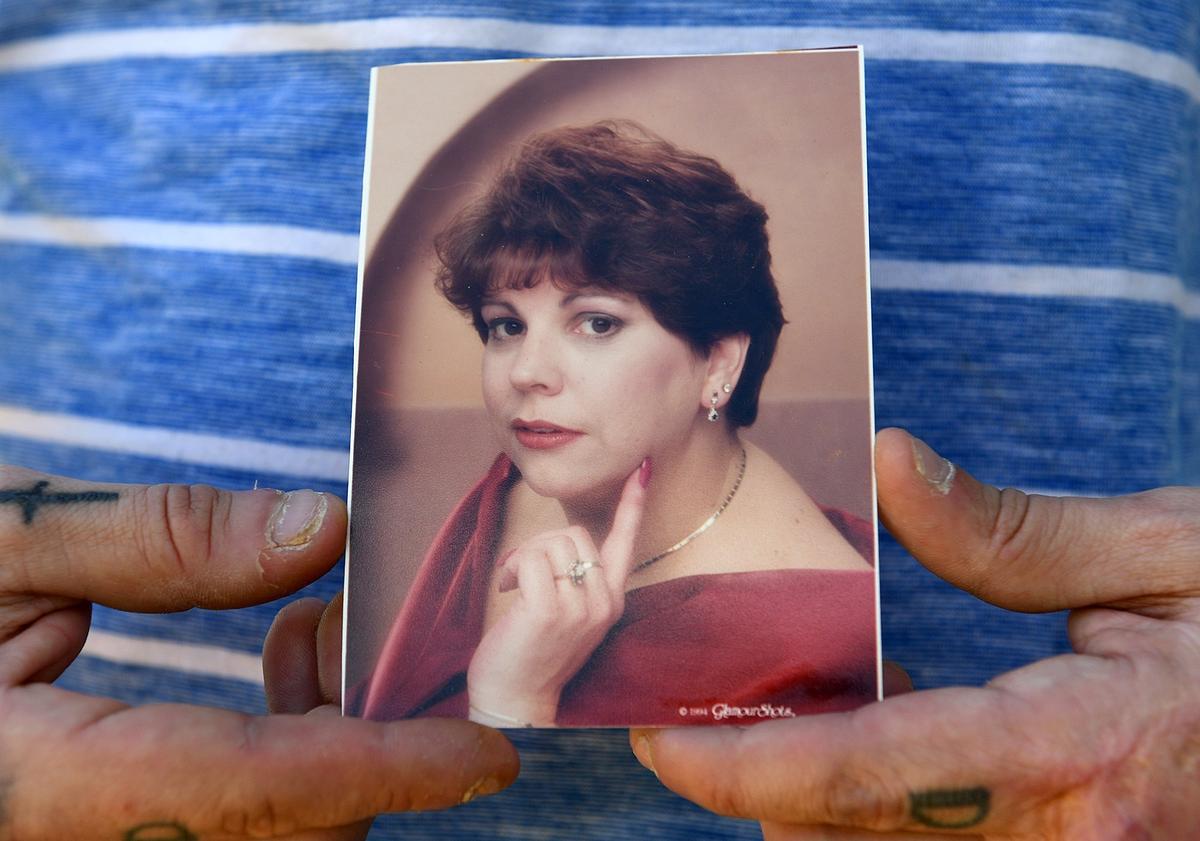 Robert Demeo holds a glamour photo of his mother, Joan Demeo, on the steps of the Royal Garden Estates mobile home where she lived and was killed April 18.