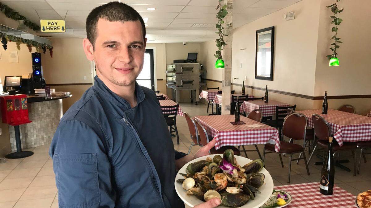 Chef Eugenio Rizzo holds a platter of Linguini Pescatore, which is mussles, clams, and shrimp sauteed in special sauce, served over linguini pasta.