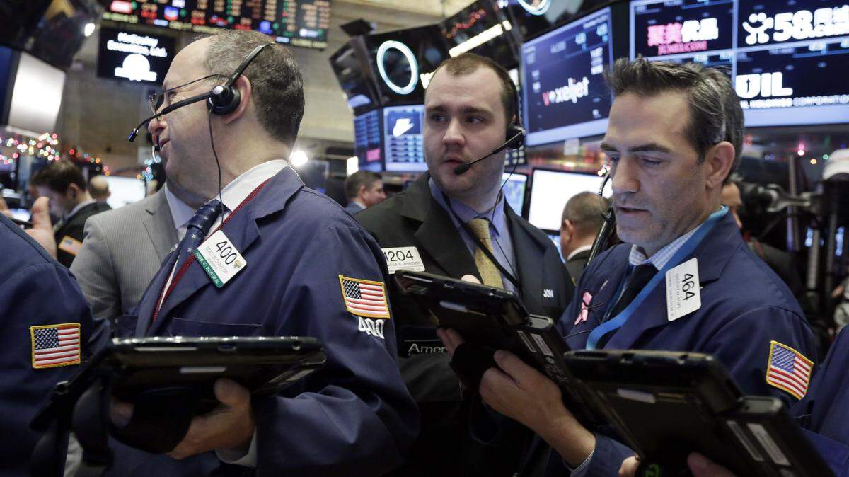 Traders Gordon Charlop, left, Nathan Wisniewski, center, and Gregory Rowe, ork on the floor of the New York Stock Exchange on Dec. 16. ASSOCIATED PRESS