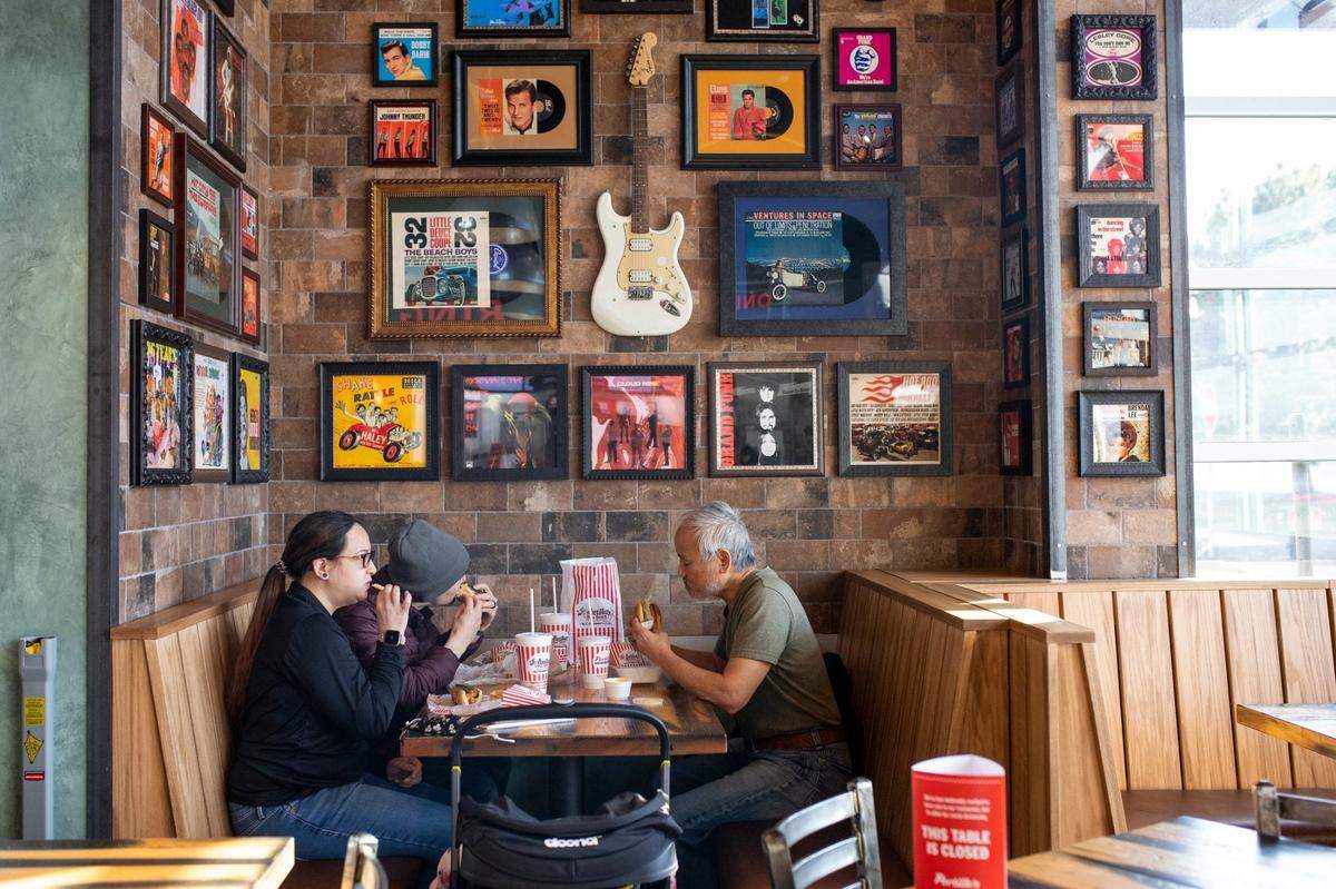 From left, Courtney Boyd, Devlin Boyd and George Shiau eat lunch at Portillo's on March 8, 2021, in Sterling Heights. It was the location's first day being open to the public. Portillo's is most well-known for their Chicago-style hot dogs, but offer's a wide assortment of food.Portillos 03072021 At 392