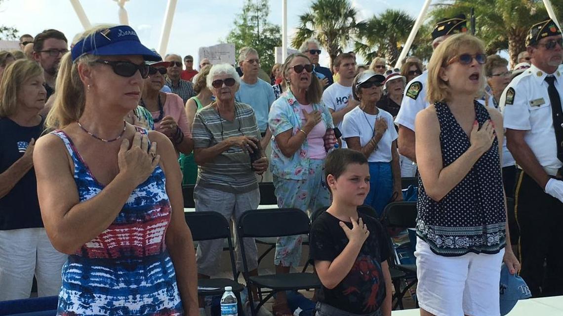 Spectators at the 2016 Flag Day Celebration at Sarasota National Cemetery on Sunday sing to honor America with their hands over their hearts.