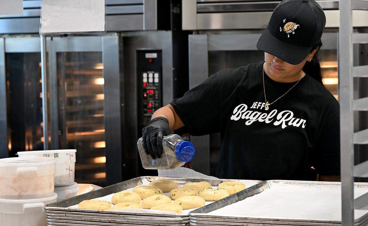 An employees adds spices to boiled bagels before baking at Jeff’s Bagel Run at 14624 State Road 70 East on Oct. 6, 2025.