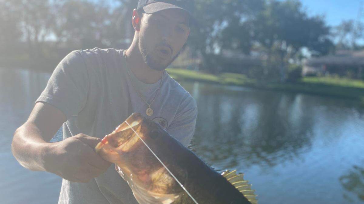 John Schwenn holds a bass caught fishing a pond with a Texas-rigged paddle tail worm in early April 2022.