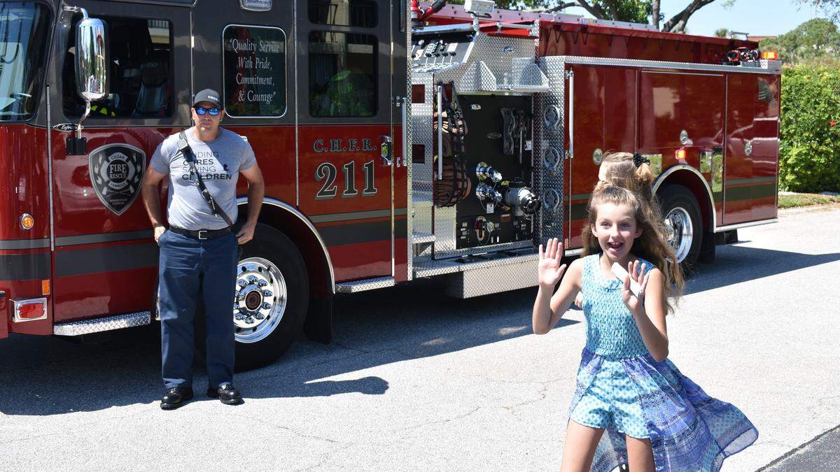 Francesca Friedel reacts to a surprise escort from a Cedar Hammock Fire Rescue truck before her annual fundraising event at Wild Oak Bay.