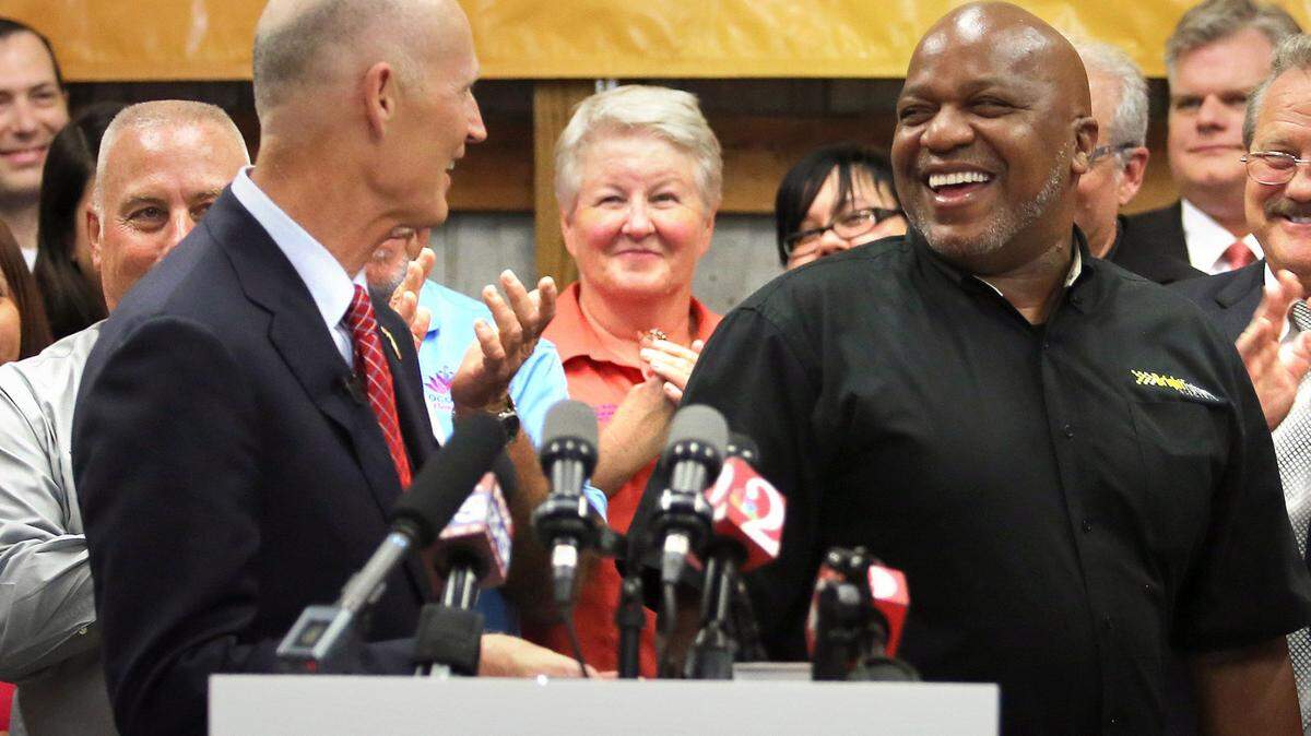 Florida Gov. Rick Scott jokes with manager Noble Thomas before delivering remarks on jobs growth during a visit to Bright Future Electric, an electrical contractor business with offices in Florida and Alabama, Thursday, June 11, 2015, in Ocoee, Fla. (Joe Burbank/Orlando Sentinel via AP)