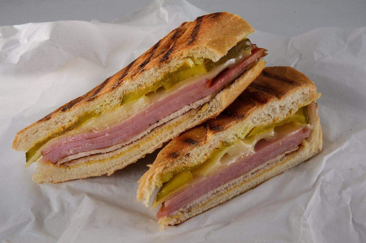 A traditional Cuban sandwich recipe calls for sliced ham, roast pork with a citrusy marinade (called mojo) and Swiss cheese layered in a loaf of Cuban bread. The sandwich is then garnished with pickles and mustard. (Zbigniew Bzdak/Chicago Tribune/MCT)