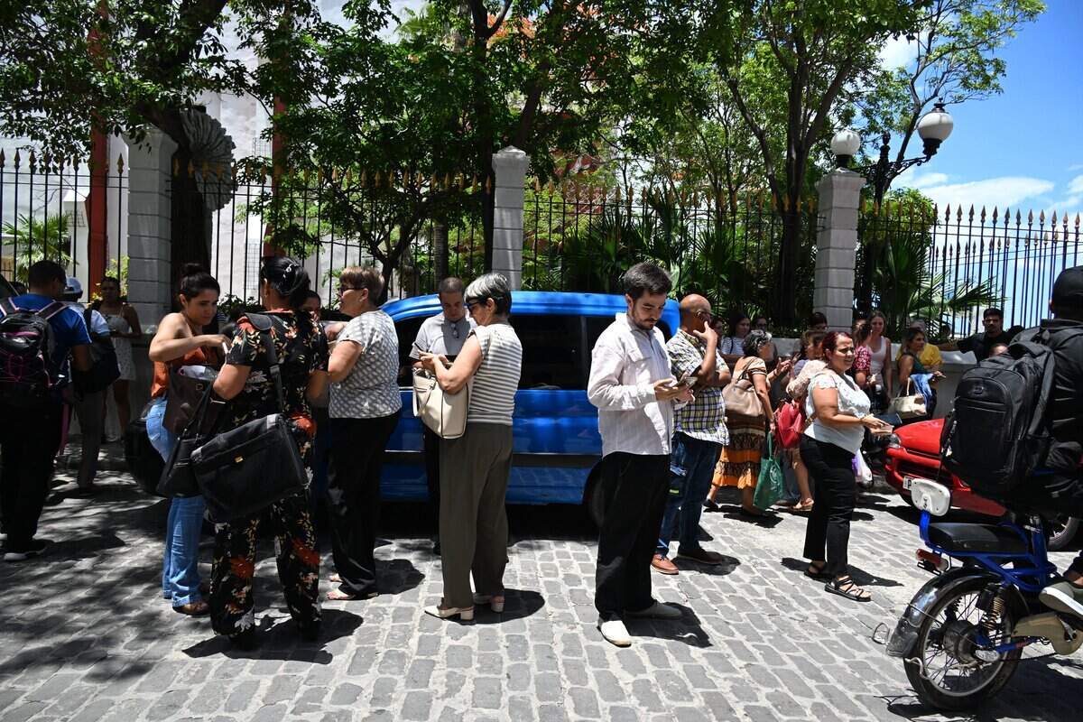 Workers check their cell phones after a tremor caused by a 6.5-magnitude earthquake in Havana, on June 8, 2026. A strong earthquake struck off the coast of western Cuba on June 8, 2026, with AFP journalists in Havana reporting 20 seconds of shaking that forced Cubans out of buildings and into the streets. The US Geological Survey reported that the quake was 6.1 magnitude and struck about 62 miles (100 kilometers) off the island's western tip. (Photo by YAMIL LAGE / AFP via Getty Images)
