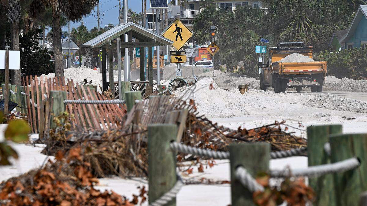 Heavy work trucks drive along Gulf Drive in Bradenton Beach after Hurricane Helene on Oct. 2, 2024.