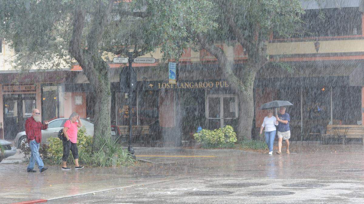 People walk in the rain along Old Main Street, as a front moves over Manatee County on Friday, bringing cooler temperatures and breezy conditions to the area. 
 GRANT JEFFERIES/Bradenton Herald