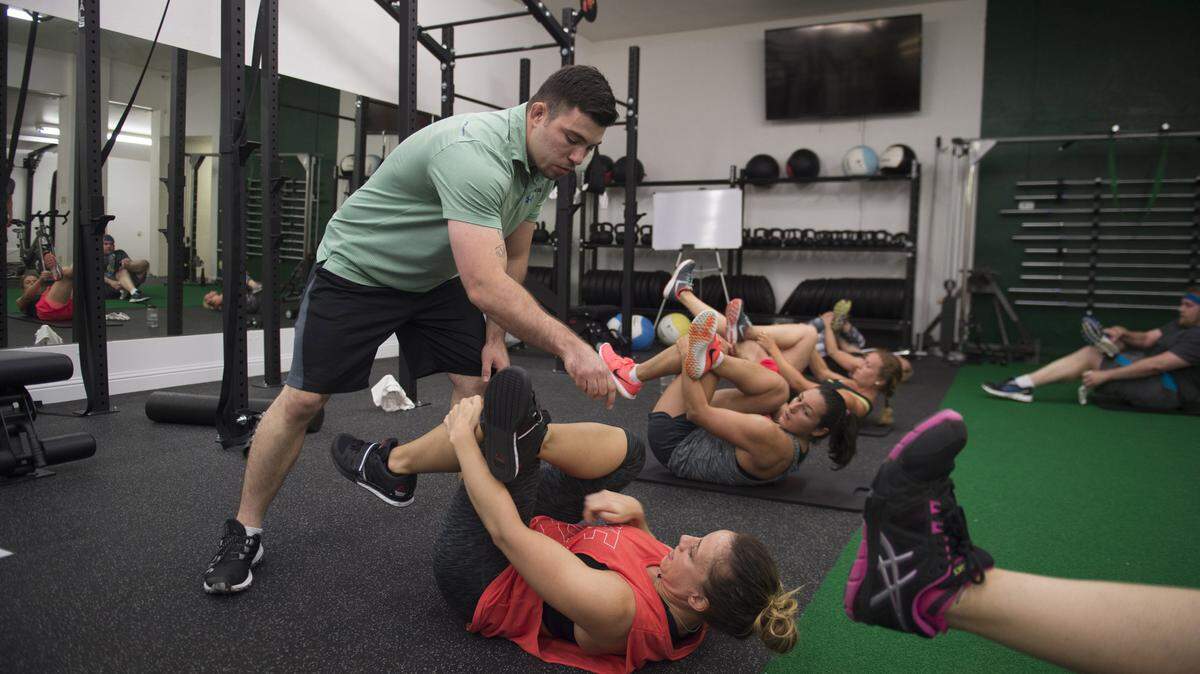 Trainer Mike Orozco helps Deidra Bielicka with leg placement in the warm-down period during high intensity interval training, also known as HIIT, at HIIT Fitness in Sacramento, Calif., on May 2. TNS