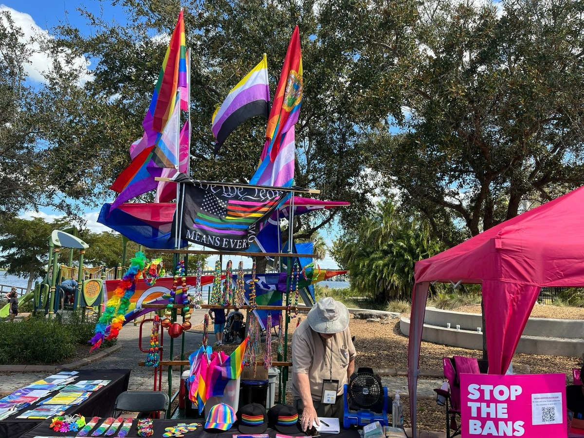 A rainbow-colored Florida State flag waves, while a vendor prepares a booth during the 7th annual Manatee County Pride festival at Riverwalk Park in March.