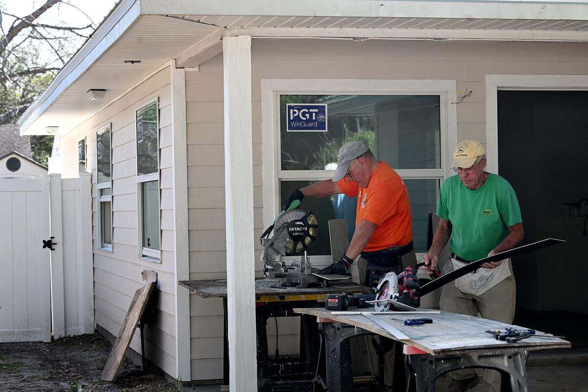 Manatee County Habitat for Humanity volunteers work on cutting flooring for a home in Palmetto that is being remodeled.