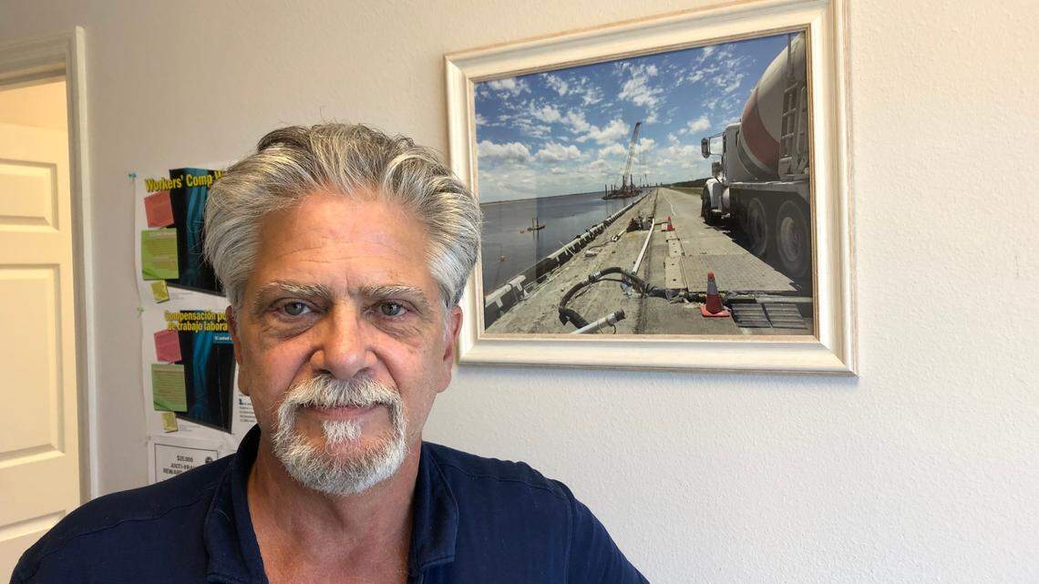 Paul Falco stands in front of a photograph showing cellular concrete being installed along Lake Parrish at the FPL power station.