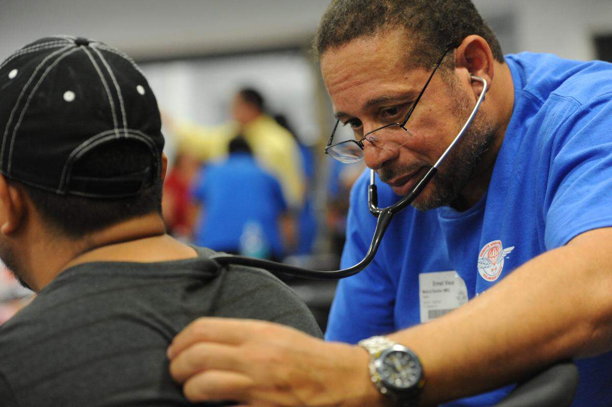 Remote Area Medical needs volunteers for its clinic Oct. 13-14 in the Bradenton area. Dr. Ernst Vieux  is shown above at a pervious clinic examining a patient at Manatee Technical College.