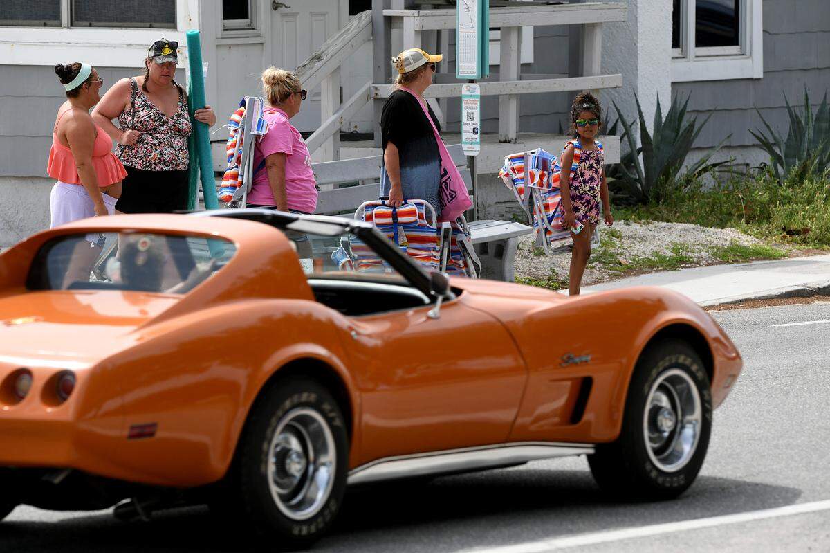 Visitors to Cortez Beach wait to cross the road Friday. Rain bands from a tropical disturbance impacting South Florida had not made their way to Manatee County beaches mid-morning Friday. The National Hurricane Center is forecasting the system to slightly strengthen into a tropical storm.