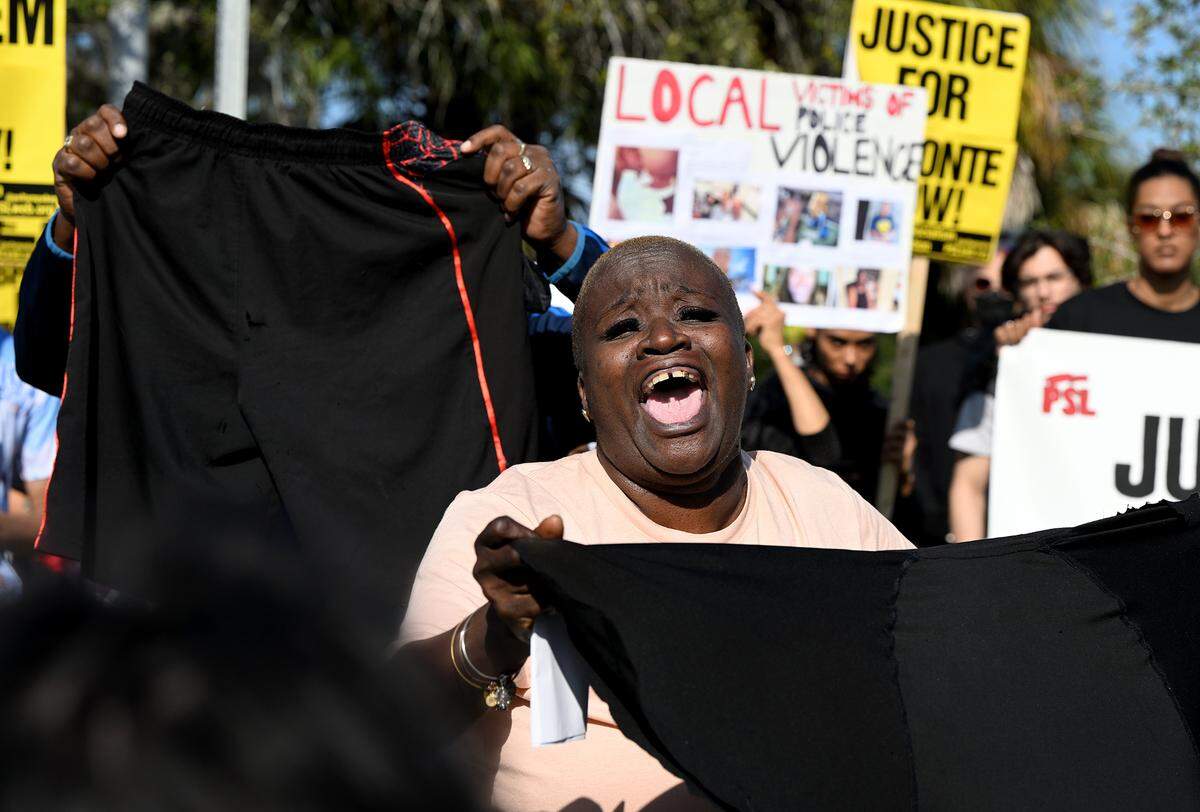 Tracey Washington sings during a Sunday, Jan. 7, 2024, protest, holding the clothes her son, Breonte Johnson-Davis, was wearing when he was taken into custody by the Palmetto Police Department. Dozens of protesters gathered to demand answers following the November death of 36-year-old Johnson-Davis, who died shortly after Palmetto police officers used a stun gun on him, according to a police report.
