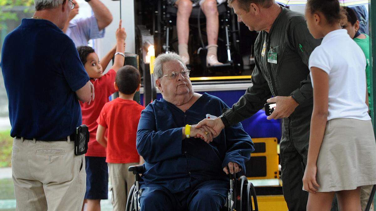 Oneco Elementary teacher and U.S. Air Force veteran Peter Brock shakes U.S. Army veteran Joseph Cashman's hand as he gets off a bus from Bay Pines, which brought veterans to the school to be served a meal by students and given a handmade lap blanket in December 2015