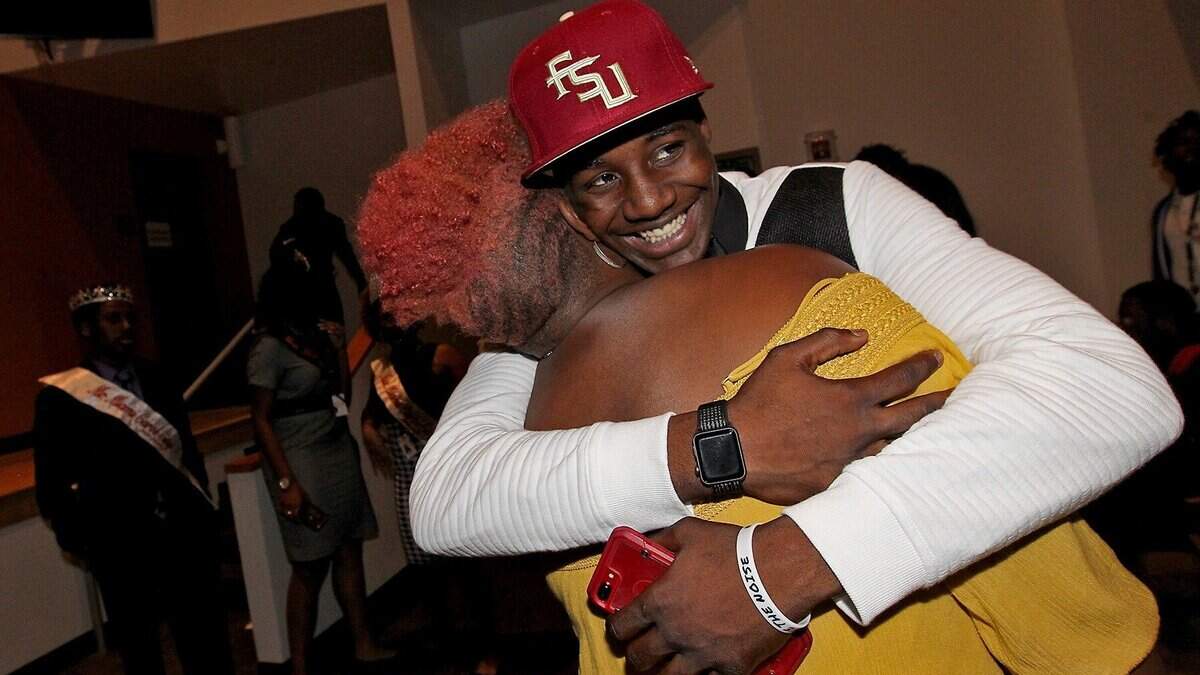 Carol City High School football player Jarvis Brownlee gets a friendly hug after signing with Florida State University at the football signing day ceremony at Carol City Senior High School on Wednesday December 19, 2018.